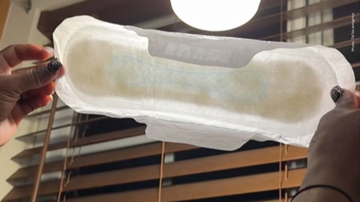 vrouw die maandverband met zwarte vlekken vasthoudt